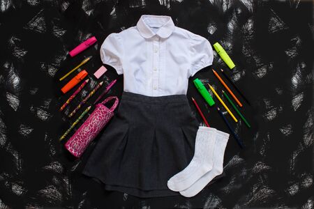 White shirt, grey skirt, white socks and stationery on black background. Uniform. The first of september, new school year supplies. Back to school banner, education concept.Top view,flatlay,copy spaceの写真素材