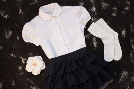 White shirt and socks, hair accessories, grey skirt and stationery on black background. Uniform, outfits. The first of september, new school year. Back to school,education.Top view,flatlay,copy space.の写真素材