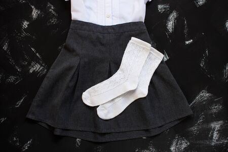 White shirt and socks, grey skirt and stationery on black background. Uniform, outfits. The first of september, new school year. Back to school banner, education concept. Top view, flatlay,copy space.の写真素材