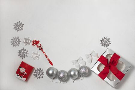 Christmas composition of red and silver decorations, gift box with ribbon bow, balls and snowflakes on a white background, flatlay. New year, winter, holidays concept. Top view, copy space.の写真素材