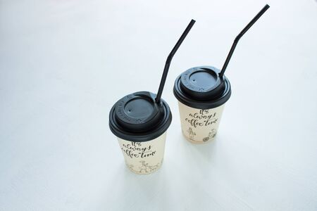 Kraft paper coffee cup with black lid and tubule from street shop on light background. Lifestyle concept, take away drinks, minimalistic style. Copy space, top view.の写真素材