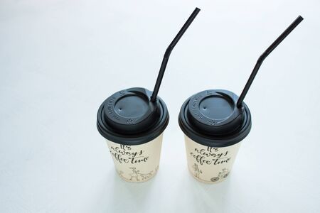 Kraft paper coffee cup with black lid and tubule from street shop on light background. Lifestyle concept, take away drinks, minimalistic style. Copy space, top view.の写真素材