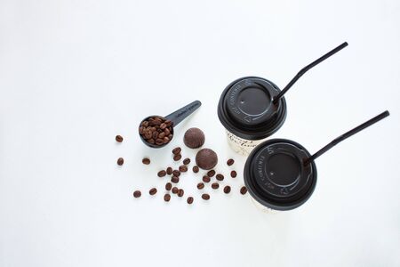 Kraft paper coffee cup with black lid and tubule from street shop with a spoon of coffee beans on light background. Dark chocolate candies,sweets.Lifestyle concept,take away drinks.Copy space,top viewの写真素材