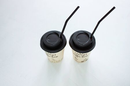 Kraft paper coffee cup with black lid and tubule from street shop on light background. Lifestyle concept, take away drinks, minimalistic style. Copy space, top view.の写真素材