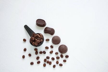 Dark chocolate candies,sweets with a spoon of coffee beans on light background. Lifestyle concept,kraft paper coffee cups with black lid, take away drinks. Copy space,top view.の写真素材