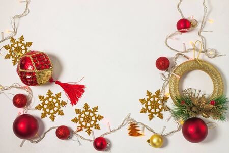 Christmas present box with red ribbon, gold decorations, balls, wreath, snowflakes and lights on a white background. New year concept, holidays composition, winter flatlay. Top view. Copy space.の写真素材