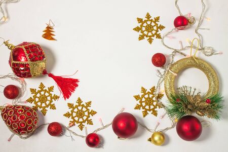 Christmas present box with red ribbon, gold decorations, balls, wreath, snowflakes and lights on a white background. New year concept, holidays composition, winter flatlay. Top view. Copy space.の写真素材