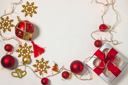 Christmas present box with red ribbon, golden decorations, balls, snowflakes and lights on a white background. New year 2020 concept, holidays composition, winter flatlay. Top view. Copy space.の写真素材