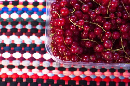 Red currant in a box on a colourful fabric background. Tasty fresh berries, vitamins, vegan, natural, raw food. Healthy diet. Copy space, top view.の写真素材