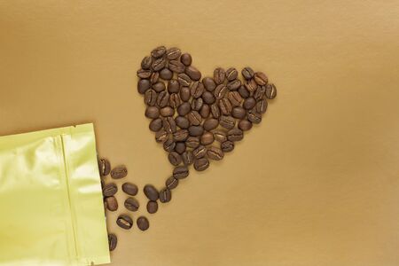 Gold foil bag with coffee beans on golden background. Packaging template mockup. Aluminium package for tea, flatlay.の写真素材