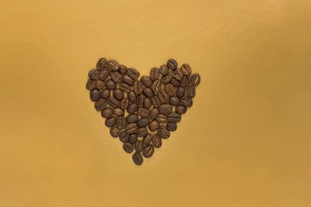 Gold foil bag with coffee beans on golden background. Packaging template mockup. Aluminium package for tea, flatlay.の写真素材