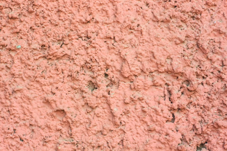 Vintage pink background. Texture of cement plaster. Rough painted wall of fiesta color. Uneven old...