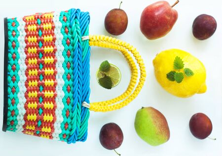 Healthy food in a basket. Zero waste concept, colorful reusable eco bags. Mix of different fruits on a white background, shopping packaging, top view, flatlay.Pears, plums, mint leaves,lime and lemon.の写真素材