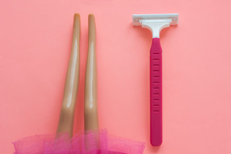 Disposable shaving machine for women and dolls legs in a skirt on a pink pastel background. Removal...