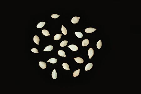 Pumpkin seeds in a ball shape on a black background. Creative minimalism, dark and moody food photography. Copy space, squash top view, flat lay. Halloween concept.の写真素材