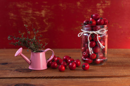 Immunity boosting treatments. Natural thyme, mint herbs and rosehip berries in a jar on a wooden...