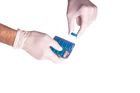 Male doctors hands in rubber gloves holding a plate of blue pills on white backgound isolated....
