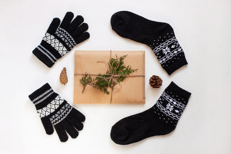 New year 2020 flatlay. Christmas black ornamental socks and gloves, gift box in eco kraft paper. Mock up template design. Winter holiday decorations,pine cones,minimal style,white background. Top viewの写真素材