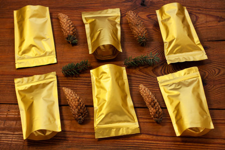 Golden pouch bags open composition flat lay style, pattern. Christmas gift, New year decorations on rustic wooden background. Trendy tea,coffee packaging mockup.の写真素材