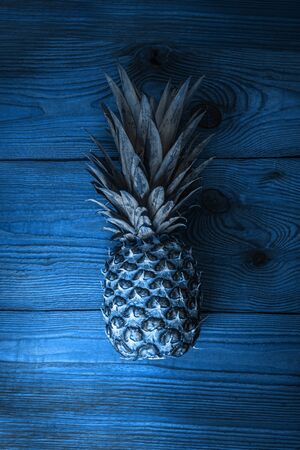 Blue pineapple on wooden background flatlay. Color trends 2020, tropical fruits, diet, slimming vegan foods, weight loss. Minimal photo, top view, trendy social media banner.Creative minimalism style.の写真素材