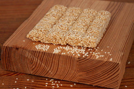 Honey bars with sesame seeds close-up on wooden background. Gozinaki sweets. Traditional oriental...