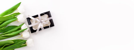 Spring website header template. White tulip black gift box with silver ribbon on light background...