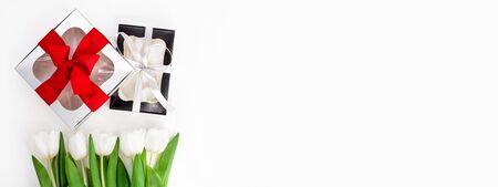 Spring website header template. White tulips, black and silver gift boxes with ribbons on light background flat lay. Bouquet greeting card. Copy space bannerの写真素材