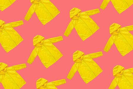 Yellow raincoat on pink color background isolated pattern. Funny outwear autumn style clothes. Enjoying rainfall. Happy rainy day concept, Hello Fall greeting card flat lay. Bright rain jacket textureの写真素材