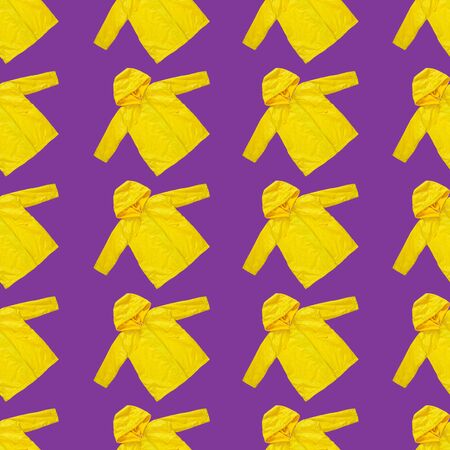Yellow raincoat on purple color background seamless pattern. Funny outwear autumn style clothes flat lay. Enjoying rainfall texture. Happy rainy day concept, Hello Fall.Bright kids outdoor rain jacketの写真素材