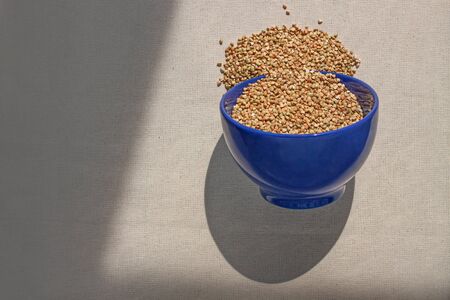 Green buckwheat in blue porcelain bowl, natural shadow.Dry unroasted whole grain superfood flat lay.Organic healthy food, weight loss, reduce inflammation,help manage diabetes,maintaining heart healthの写真素材