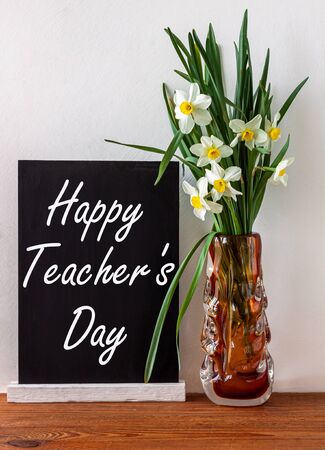 Internanional Teacher's day poster design with sign on black chalkboard and daffodils flowers on white background.Message written on blackboard display.Greeting card back to school concept bannerの写真素材
