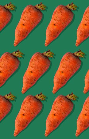 Ugly carrots regular pattern with shadows. Big deformed vegetables on green background. Trendy colors. Misshapen produce, food waste concept.Minimal creative style,pop art flat lay advertising bannerの写真素材