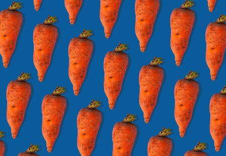 Ugly carrots regular pattern with shadows pastel background. Big deformed vegetables on pastel background.Trendy flatlayの写真素材