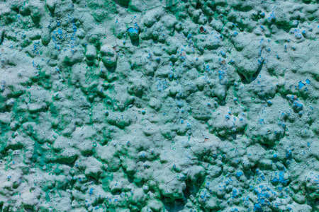 Old turquoise plaster wall texture. Retro painted putty building background with copy space. Stylish blue surface, detailed stones backdrop. Wallpaper textured screensaver front view for text design.の写真素材