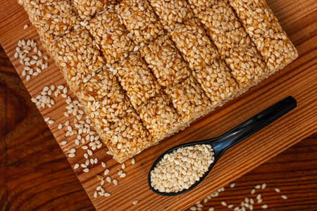 Honey bars with sesame seeds close-up on wooden background. Gozinaki sweets. Traditional oriental confection with roasted caramelized nuts. Sesame seed candy crunch. Energy bars in minimalism style.の写真素材