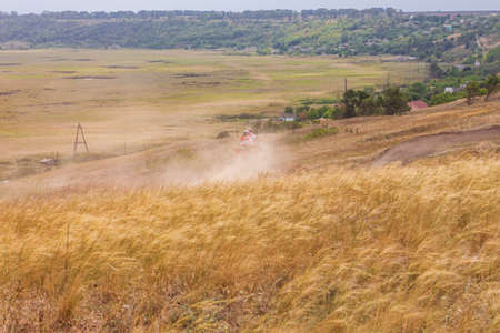 Motorcyclist rides on a wild hills. Motocross bike on beautiful rural landscape witj cloudy sky on background. Red motorcycle off-road outdoors. Berdyansk Ukraine - 06 september 2020のeditorial素材