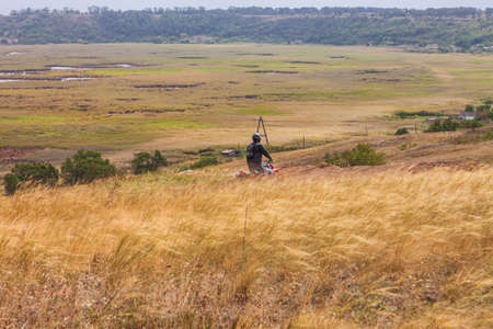 Motorcyclist rides on a wild hills. Motocross bike on beautiful rural landscape witj cloudy sky on background. Red motorcycle off-road outdoors. Berdyansk Ukraine - 06 september 2020のeditorial素材