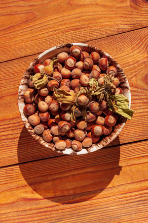 Hazelnuts in porcelain bowl on rustic wooden background. Raw fresh homegrowing nuts from house garden top view natural shadow. Organic dietary fiber, protein, vitamins source, healthy weight loss dietの写真素材