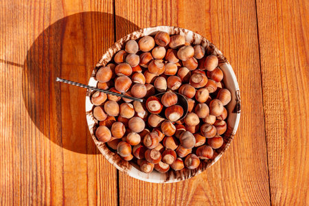 Hazelnuts in porcelain bowl on rustic wooden background. Raw fresh homegrowing nuts from house...