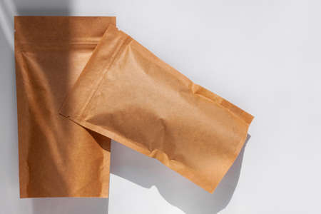 Brown kraft paper pouch bags with coffee beans top view with shadow isolated on white background. Packaging for foods and goods template mockup. Pack with clasp for tea leaves, weight products flat layの写真素材