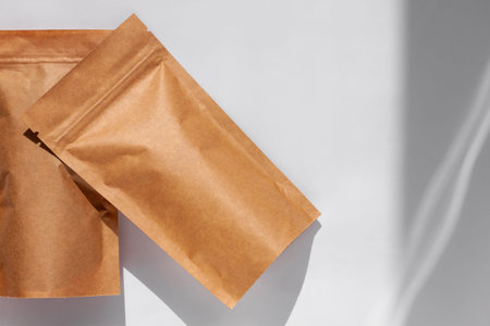 Brown kraft paper pouch bags with coffee beans top view with shadow isolated on white background. Packaging for foods and goods template mockup. Pack with clasp for tea leaves, weight products flat layの写真素材