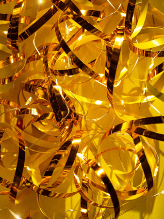 Festive yellow background Golden shimmerring shiny ribbon texture glowing decorations. Holidays New...