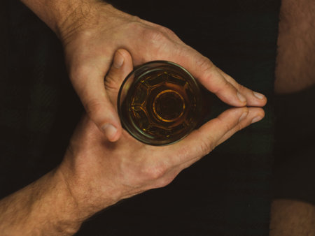 Irish man in traditional green kilt celebrating St. Patrick's Day with scotch drink glass in hand....