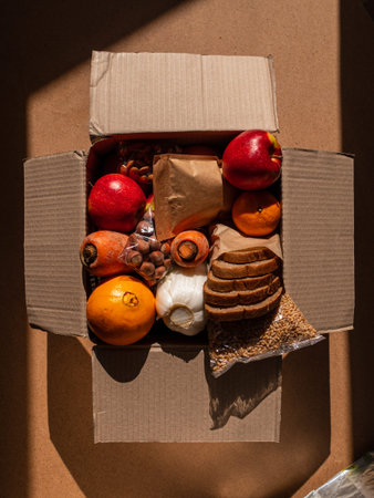Healthy food delivery flat lay harsh shadows. Take away natural organic products package. Donation box New normal online shopping safe delivery concept. Fruits vegetables carrot apple grains bread nutの写真素材