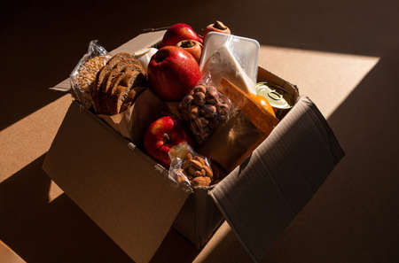 Healthy food delivery flat lay harsh shadow banner. Take away natural products package. Donation box New normal online shopping delivery concept. Fruits vegetables carrot apple grain bread cheese nutの写真素材