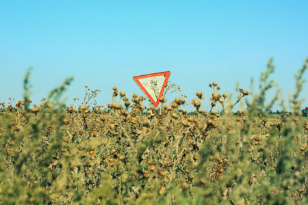 Yield sign on the road. Red traffic sign Give Way with moving motorcycle and wind turbines on...