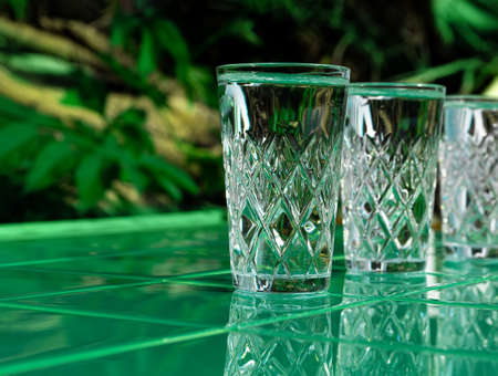 Refreshing summer drinks in crystal glasses on green bar tile background reflection harsh shadow. Cold gin vodka cocktail for hot summer day. Non alcoholic soda clear water mint tonic. Party vacationの写真素材