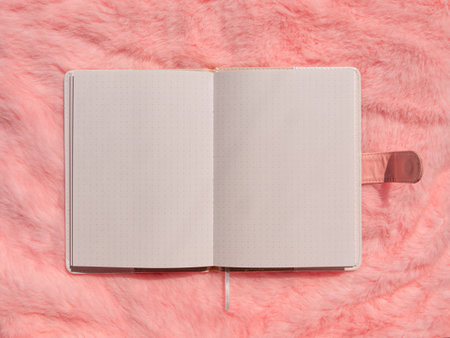 Blank notebook mockup on pink faux fur flat lay. Coral fluffy feminine fabric background top view....