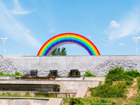 City street view with colorful rainbow on a sunny day with vibrant blue sky. LGBTQ pride concept. Park with gay rainbow symbol.の写真素材