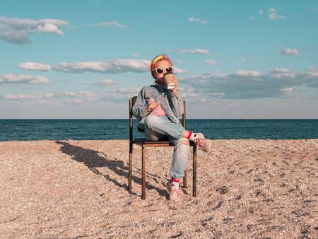 Little girl chilling resting in beach chair. Happy child smiling relaxing enjoying life sun fresh air. Lifestyle travel real people outdoor. Having fun vacation. Freedom happiness distance e-learning.の写真素材